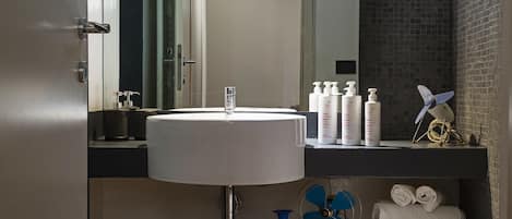 Un baño moderno con un lavamanos grande, espejo y toallero.