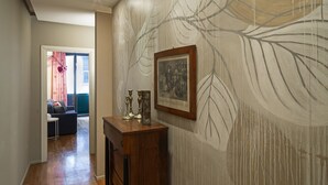 Un passadís amb un armari de fusta, un quadre emmarcat i un paper pintat al mur.