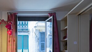 Una habitació amb un sofà, una porta corredissa de vidre que dona a un carrer estret i una prestatgeria.