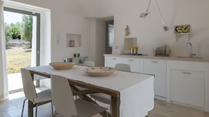 Una cocina moderna con armarios blancos, una mesa de comedor con sillas y un ventanal grande.
