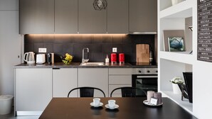 A modern kitchen with a dark backsplash, a coffee machine, a fruit bowl, and a red kettle. - UPSTREET Minimal 2BD Apt-Lycabettus view (Kaisariani)