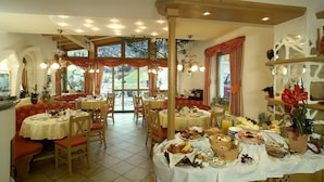 A dining area with multiple tables, chairs, and a variety of food items. - Hotel Garni Bergwelt (See)