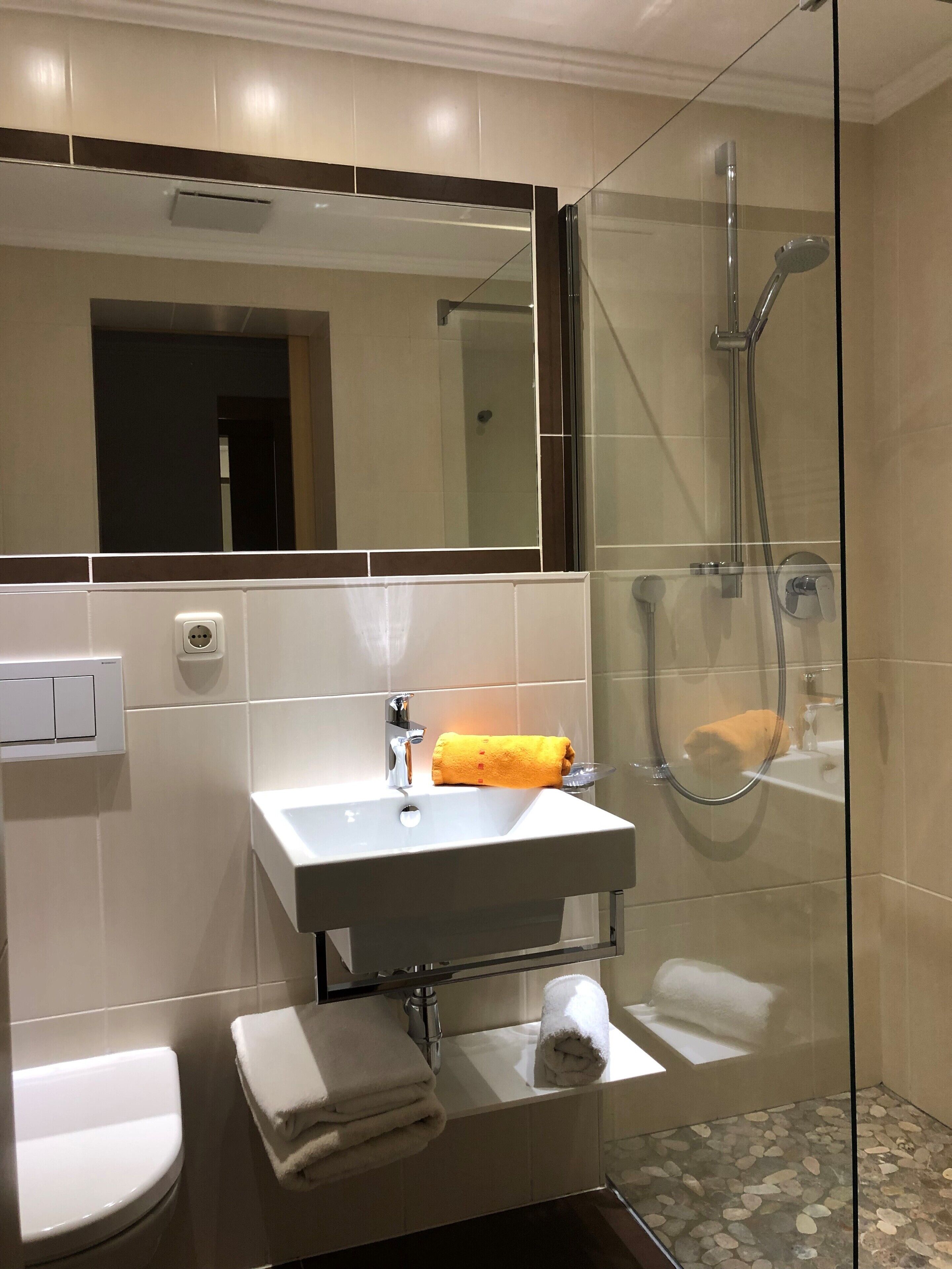 A modern bathroom with a glass-enclosed shower, a white sink, and a toilet.