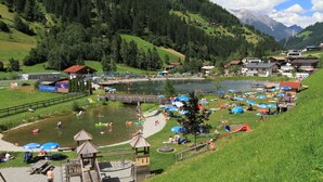 A lakeside resort with a playground, picnic areas, and a bridge connecting to a small island. - Hotel Garni Bergwelt (See)
