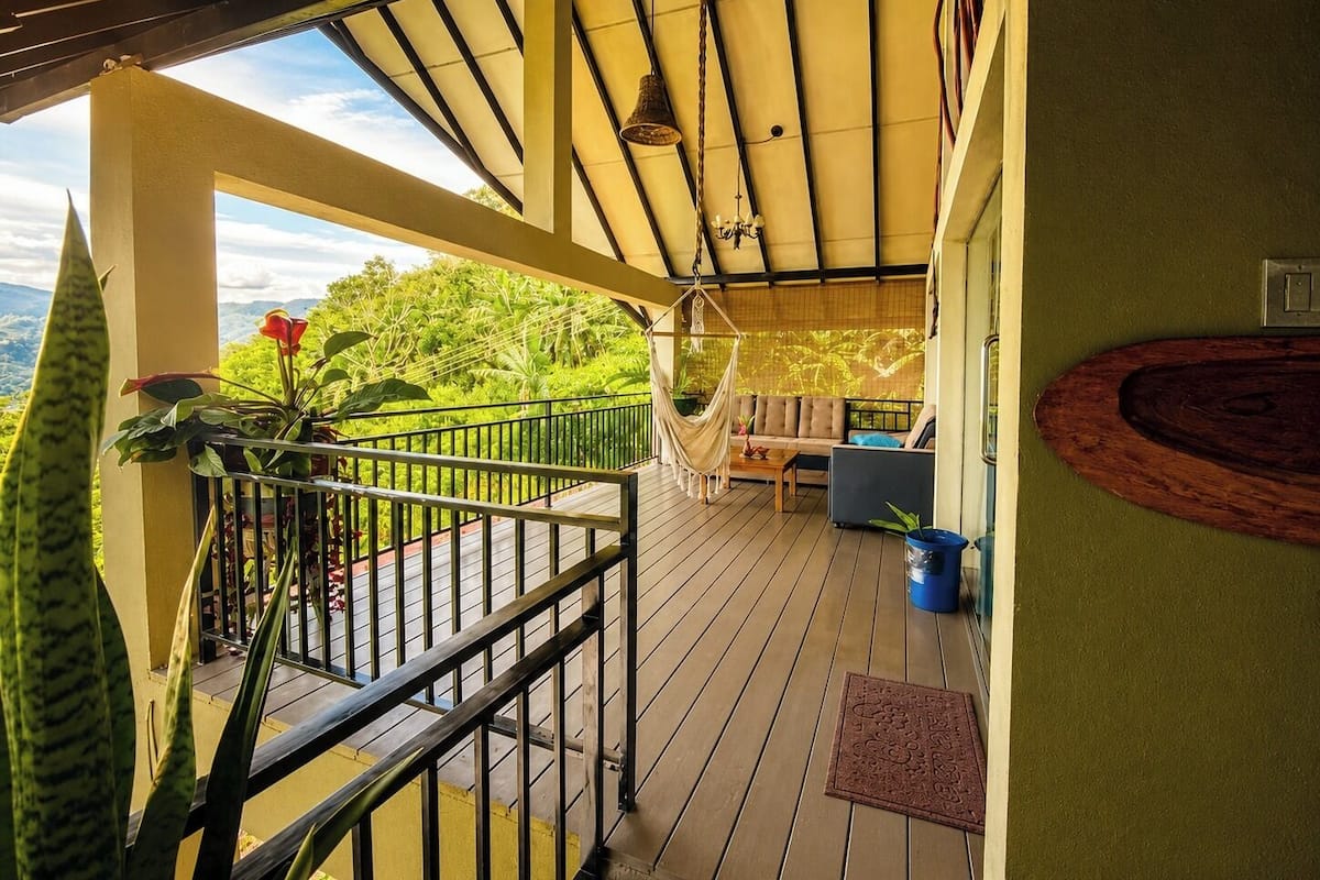 Une terrasse en bois avec une rambarde, un hamac et un canapé.