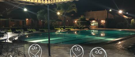 An outdoor pool area with lounge chairs and tables, surrounded by a decorative canopy.