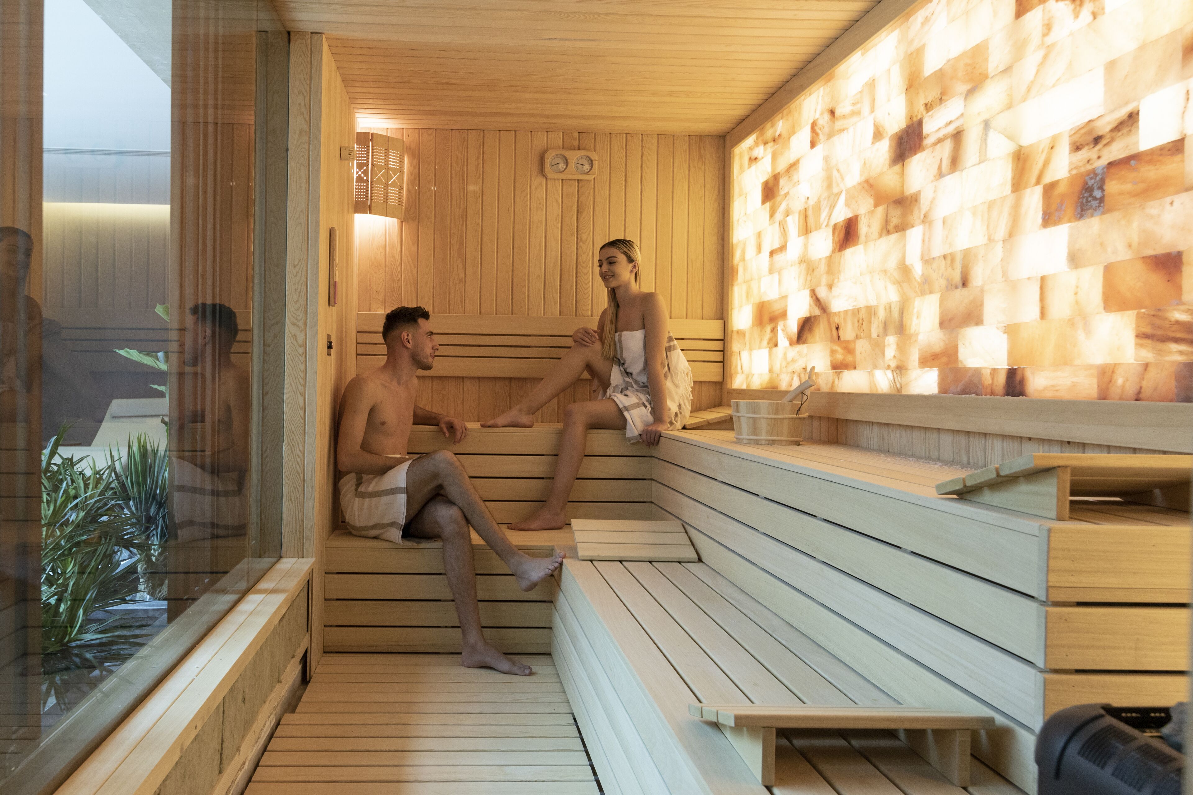 A sauna with wooden benches and a glass enclosure.