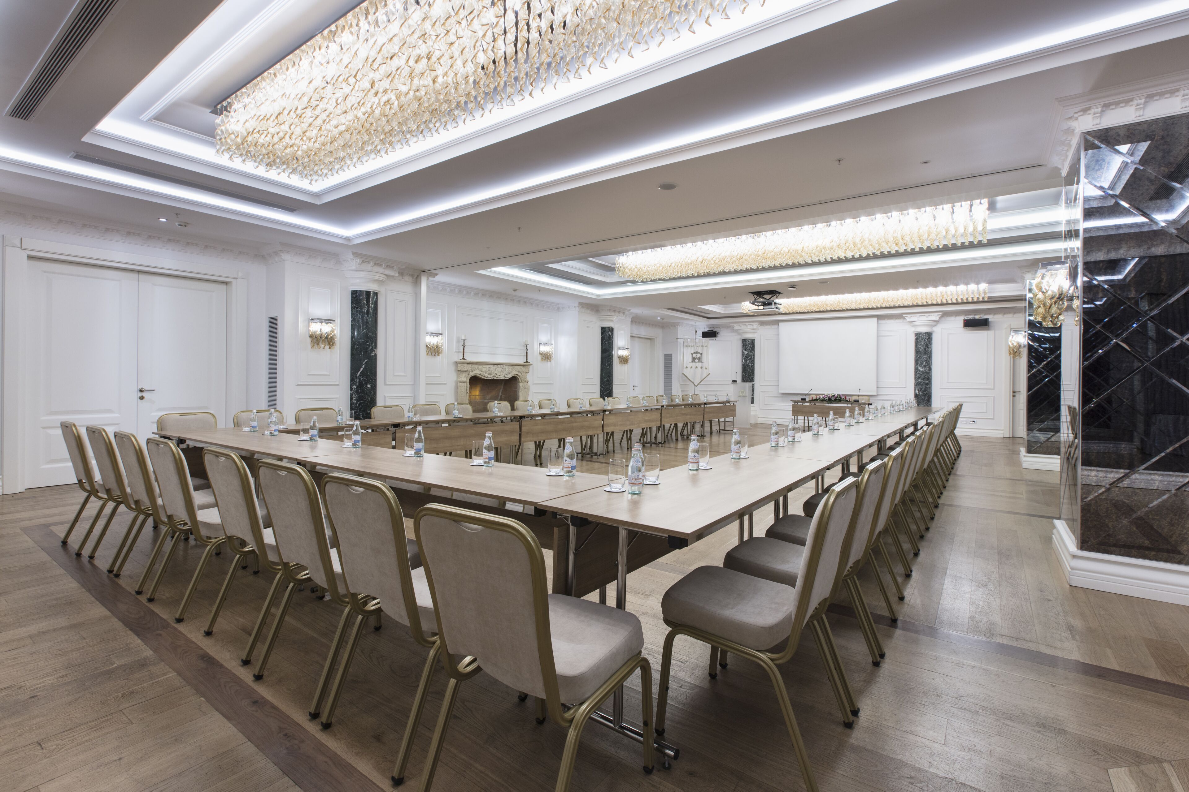 Un salón de conferencias con una larga mesa, sillas y una araña.