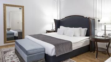 A neatly arranged bedroom with a large bed, bedside tables, a mirror, and a patterned rug.