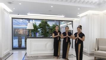 A reception area with a marble floor, a reception desk, and a large window with a view of the outside.