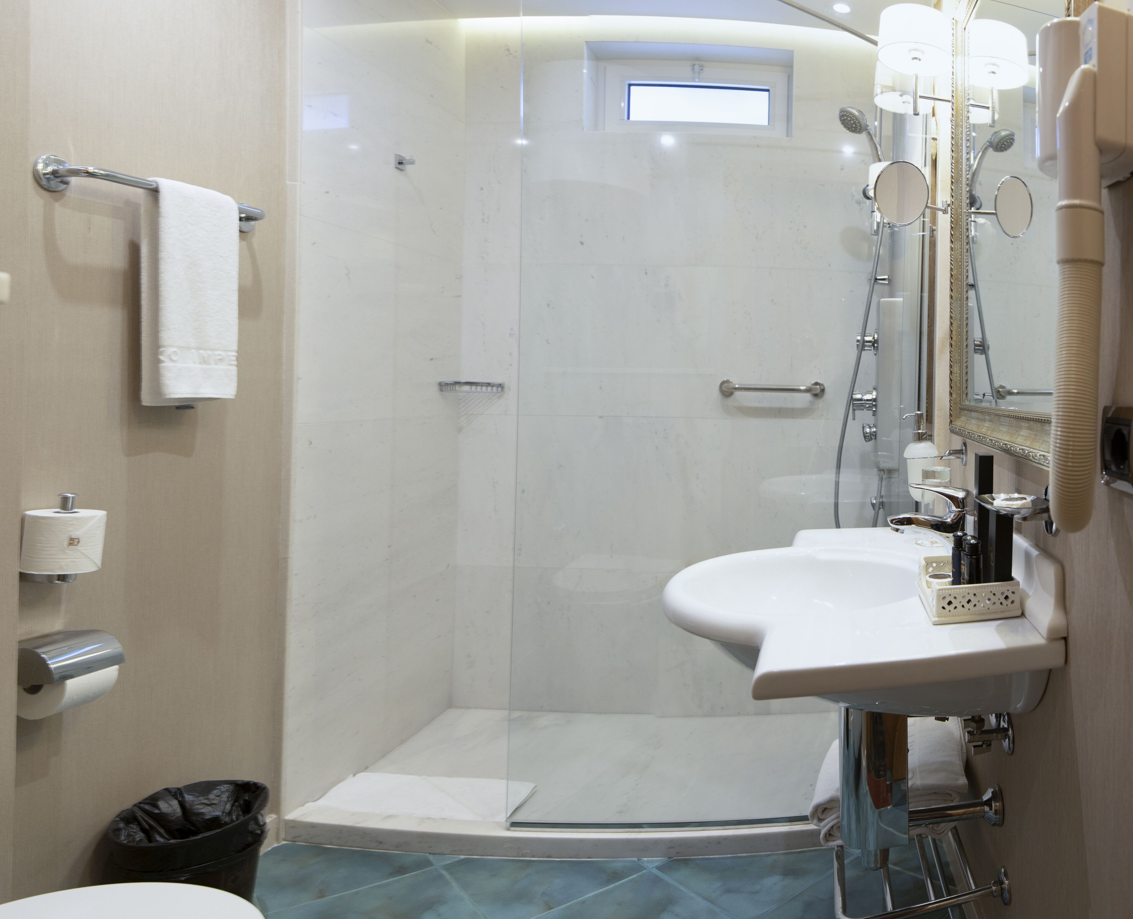 A modern bathroom with a glass-enclosed shower, a white sink, and a mirror.