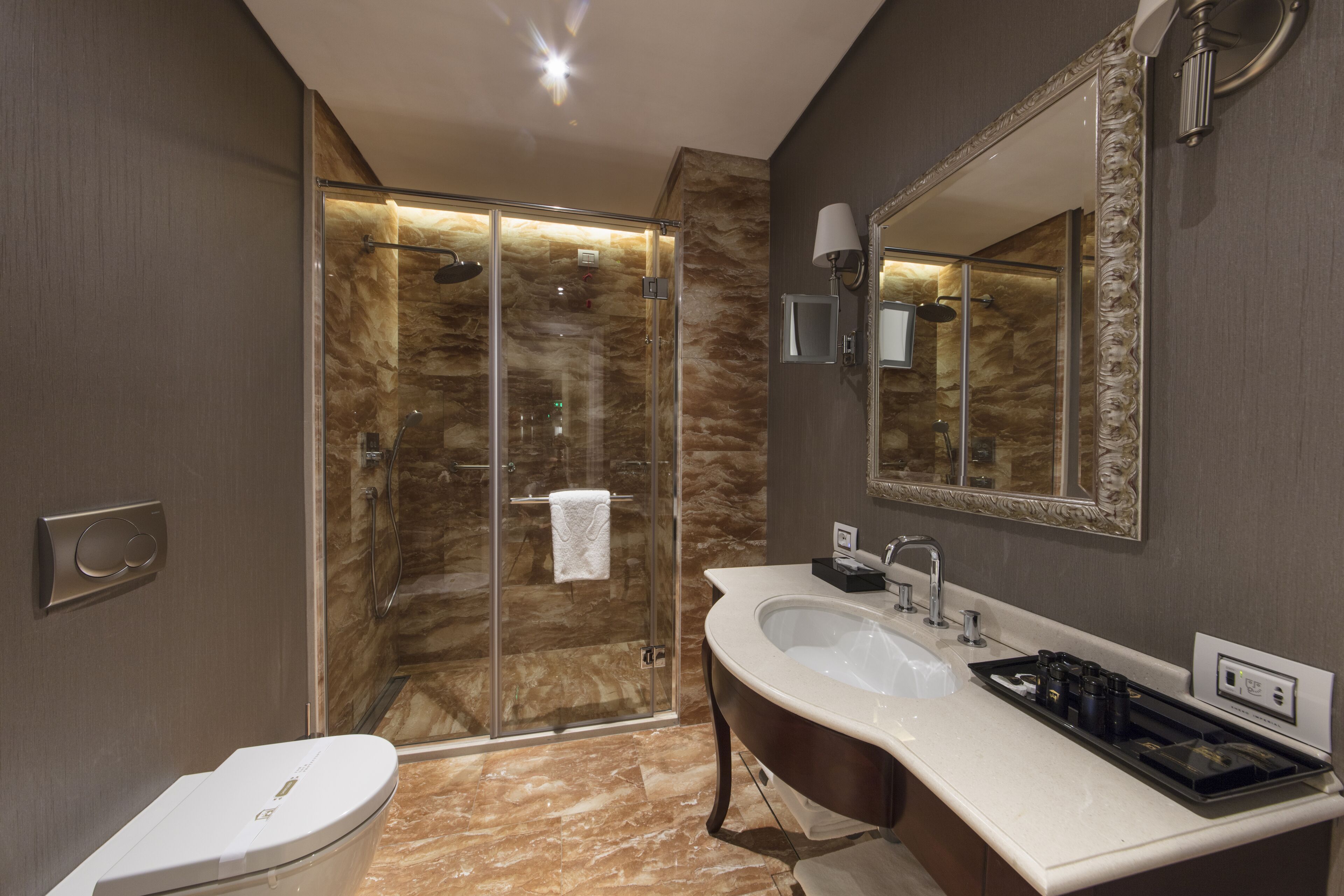 Un baño moderno con ducha de vidrio, lavabo blanco y un espejo grande.