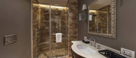 Un baño moderno con ducha de vidrio, lavabo blanco y un espejo grande.
