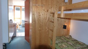 Une chambre avec un lit superposé, un mur en bois, un bureau et une chaise.