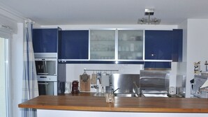 A modern kitchen with blue cabinets, a stainless steel refrigerator, and a wooden island with bar stools. - 2-bedroom sea view apartment in Trégastel with parking (Trégastel)