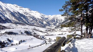 Un paysage montagneux enneigé, avec une route sinueuse et une clôture en bois.