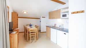 A compact kitchen with wooden cabinets, a microwave, and a dishwasher.