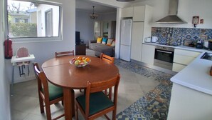 A compact kitchen with a dining area, a refrigerator, a stove, and a window providing a view of the outside. - AL at Quinta do Navio (Capelas)