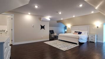 A spacious bedroom with a large bed, a chair, a desk, and a wardrobe.