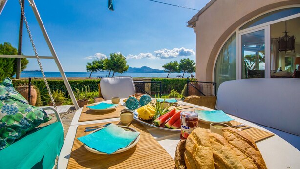 A terrace with a table set for breakfast, overlooking a scenic view of the sea and mountains. - House Puerto Pollensa Llenaire with pool (Puerto Pollensa)