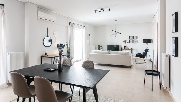 Un salon moderne comprenant un coin repas, des canapés blancs, un téléviseur et une table à manger noire.