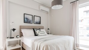 Une chambre moderne avec un grand lit, des tables de chevet, un climatiseur et une vue sur l’extérieur.