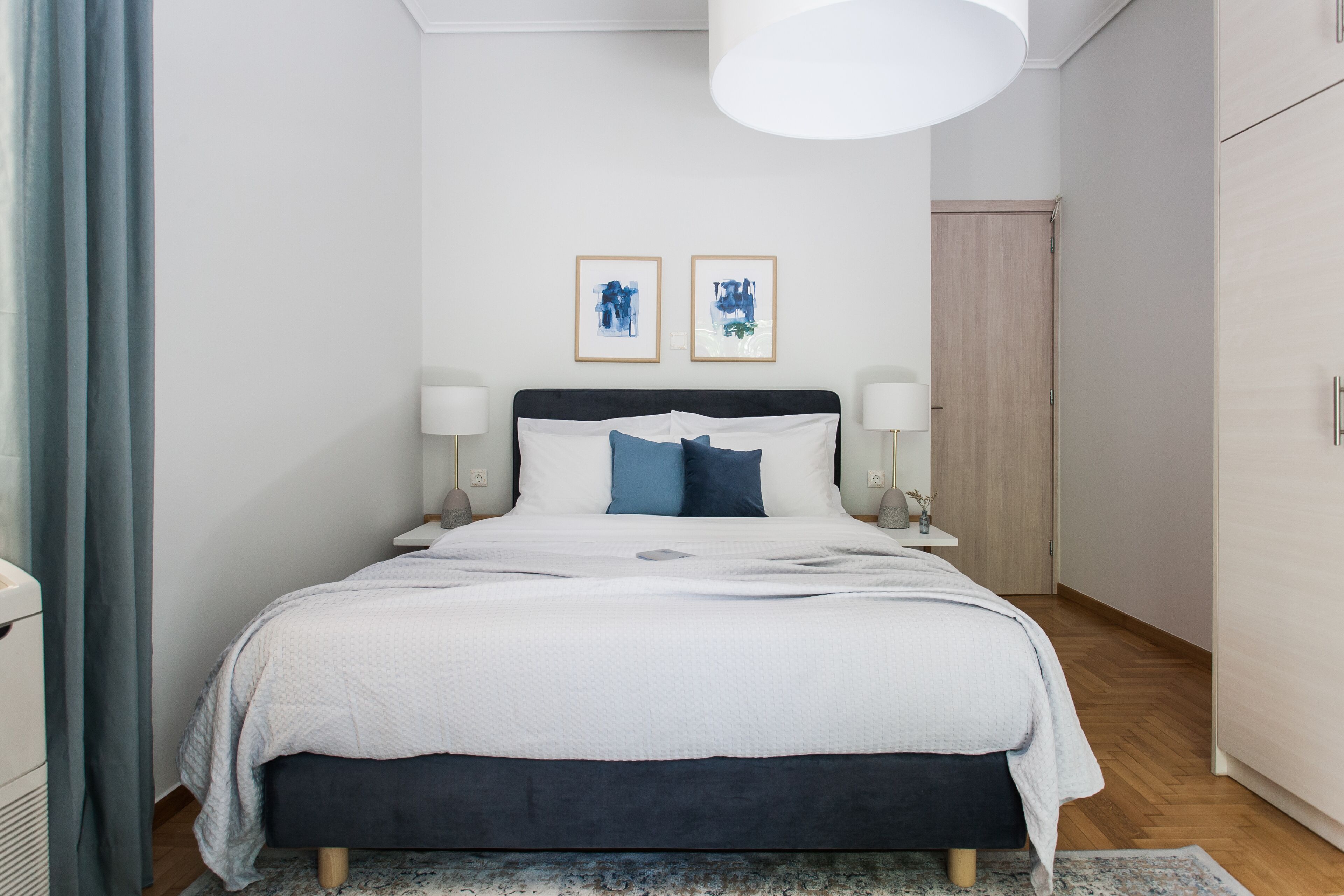 Ein modernes Schlafzimmer mit einem Bett, Nachttischlampen und einem großen Fenster.