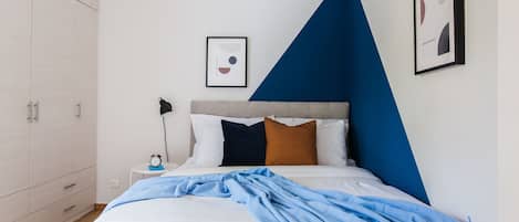 Una camera da letto con un letto, un comodino, una lampada e un armadio.