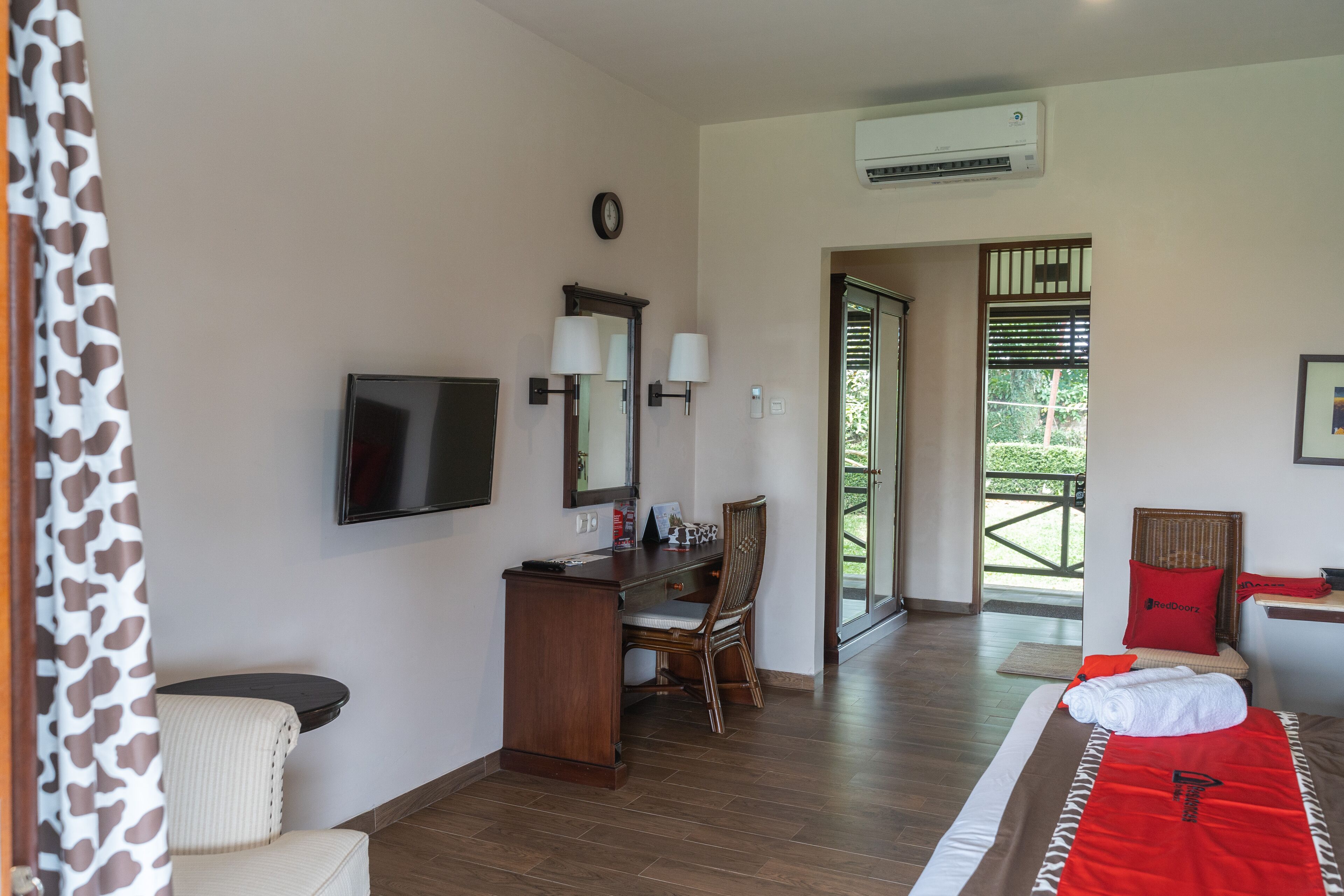 A hotel room with a desk, chair, bed, and a view of the outdoors.