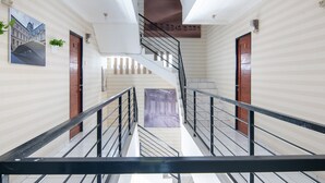 A modern interior with a central staircase, white walls, and a view of a building through a glass door. - RedDoorz Plus near Hayam Wuruk 2 (Jakarta)