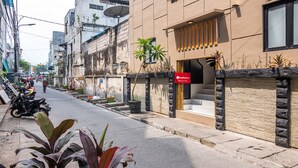 A street view with a building featuring a closed shutter, potted plants, and a satellite dish. - RedDoorz Plus near Hayam Wuruk 2 (Jakarta)