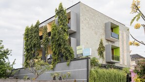 A modern building with a grey facade, balconies, and green plants. - RedDoorz @ Kerta Dalem Sidakarya (Denpasar)