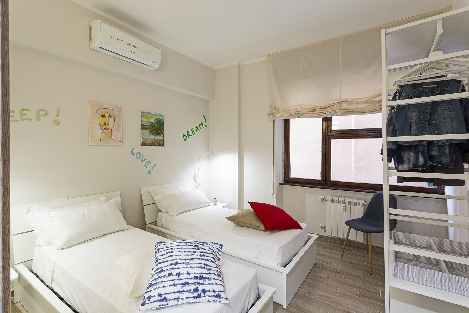 Une chambre avec deux lits, une armoire et une fenêtre avec des rideaux.