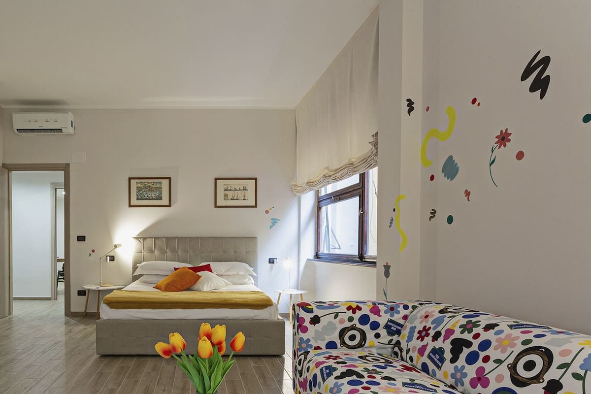 Een moderne hotelkamer met een bed, een bureau met lamp, een stoel, een bank en een raam.