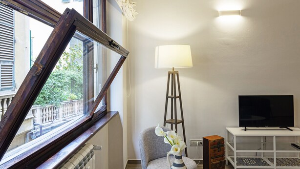 A room with a window, a standing lamp, a television, and a chair. - XXV Aprile by Wonderful Italy (Genoa)