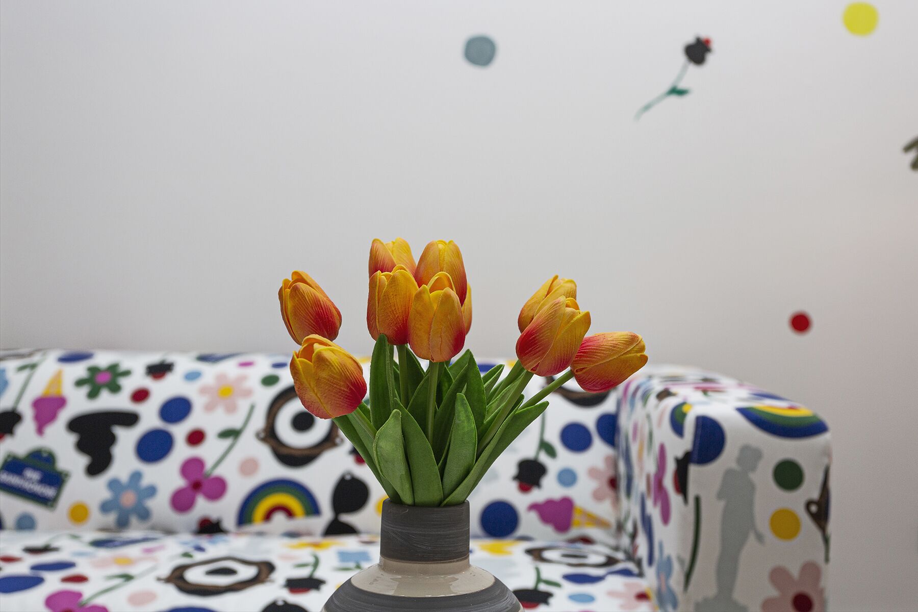 A vase with tulips on a patterned sofa.