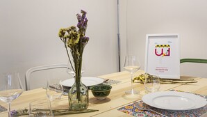 A dining table set with plates, glasses, a vase with flowers, a framed welcome sign, and a green bowl. - XXV Aprile by Wonderful Italy (Genoa)