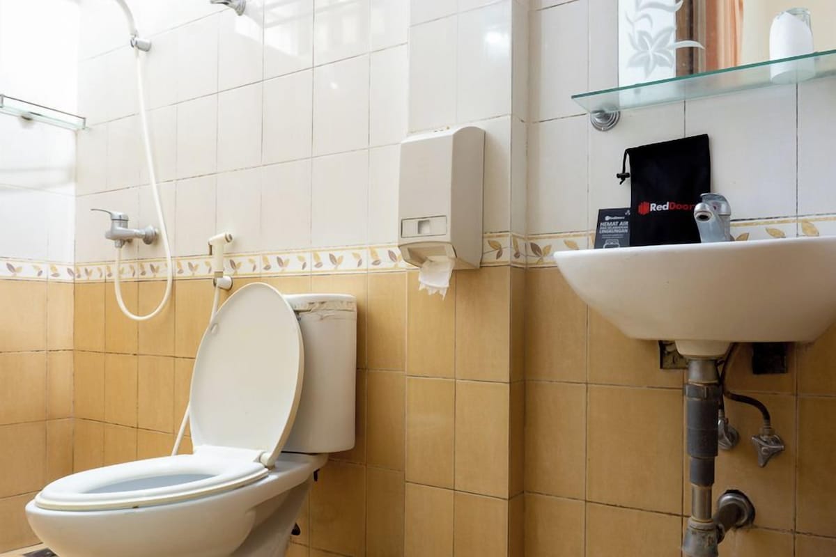 Ein Badezimmer mit Toilette, einer Glasablage für Toilettenartikel und einem Wandseifenspender.