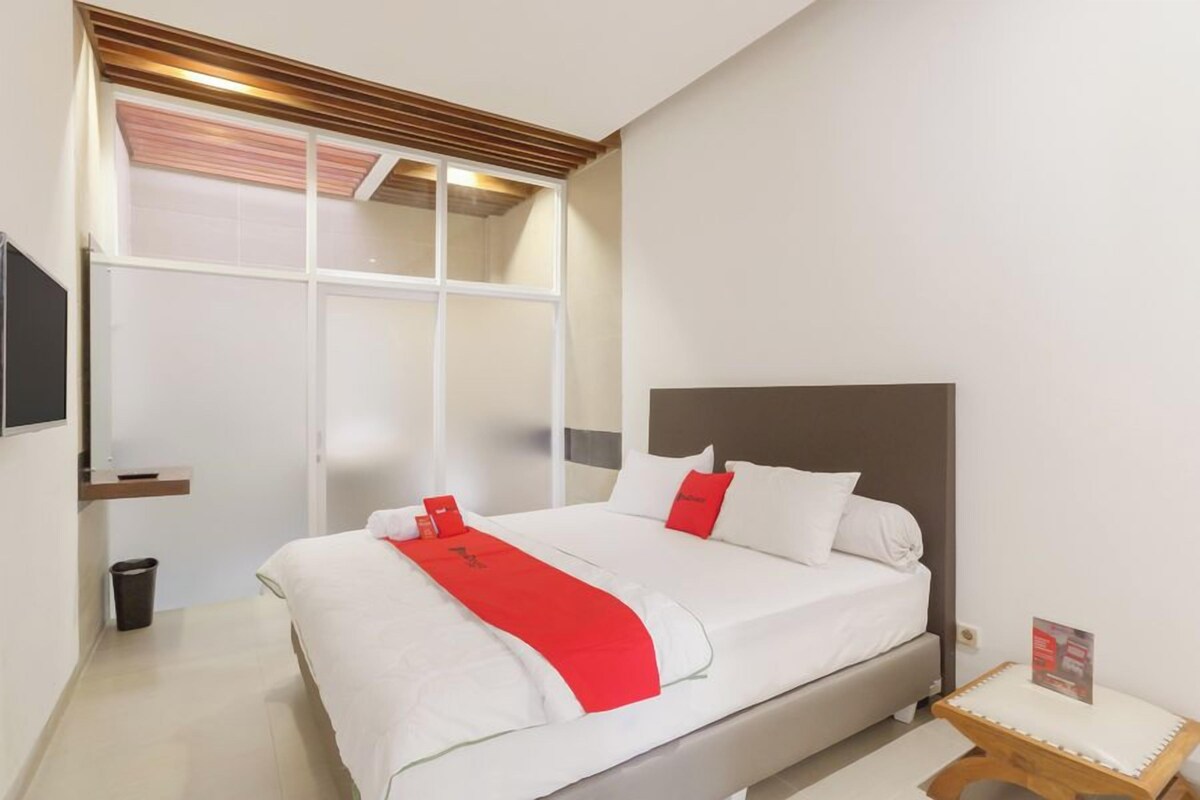 Une chambre d’hôtel avec un lit, une petite table de chevet, une télévision et une fenêtre donnant sur un paysage agréable.