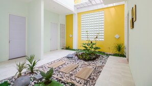 A modern interior with a yellow accent wall, a skylight, and a small garden area with plants and a pathway. - RedDoorz near UMY Yogyakarta 3 (Sleman)