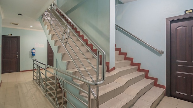 Un escalier avec des rampes en métal et des marches de couleur beige, menant à une porte portant le numéro 200.