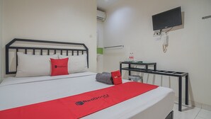 Une chambre d’hôtel avec un lit, un téléviseur fixé au mur et une petite table avec une chaise.