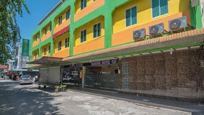 Un immeuble à plusieurs étages, doté d’une façade verte et jaune, abrite un hôtel appelé « Nagoya Hotel », reconnaissable à son enseigne.
