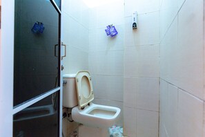 A small bathroom with a toilet, a sink, and a shower area. - RedDoorz near Hang Nadim Batam Airport (Batam)