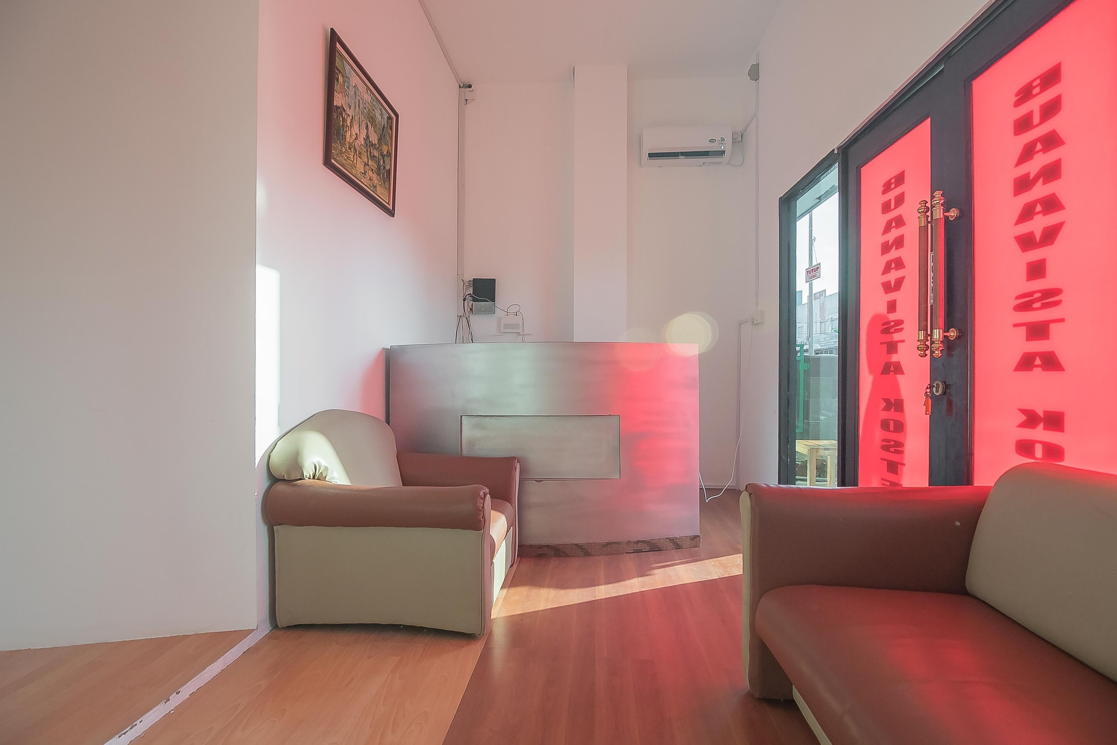 A modern living room with a sofa, a chair, and a glass partition with red text.