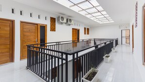 A modern interior with a glass ceiling, wooden doors, and a black railing. - RedDoorz near Pascasarjana UGM 2 (Pogung Lor)