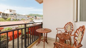 A balcony with a table and chairs, a view of buildings, and a red railing. - RedDoorz near Jembatan Siti Nurbaya Padang (Padang)