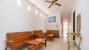 A spacious room with a wooden sofa set, a coffee table, and a decorative table with a mirror. - RedDoorz near Jembatan Siti Nurbaya Padang (Padang)