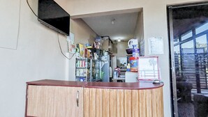 Ein Empfangsbereich mit Holztresen, einem an der Wand befestigten Fernseher und Blick durch eine Glastür.