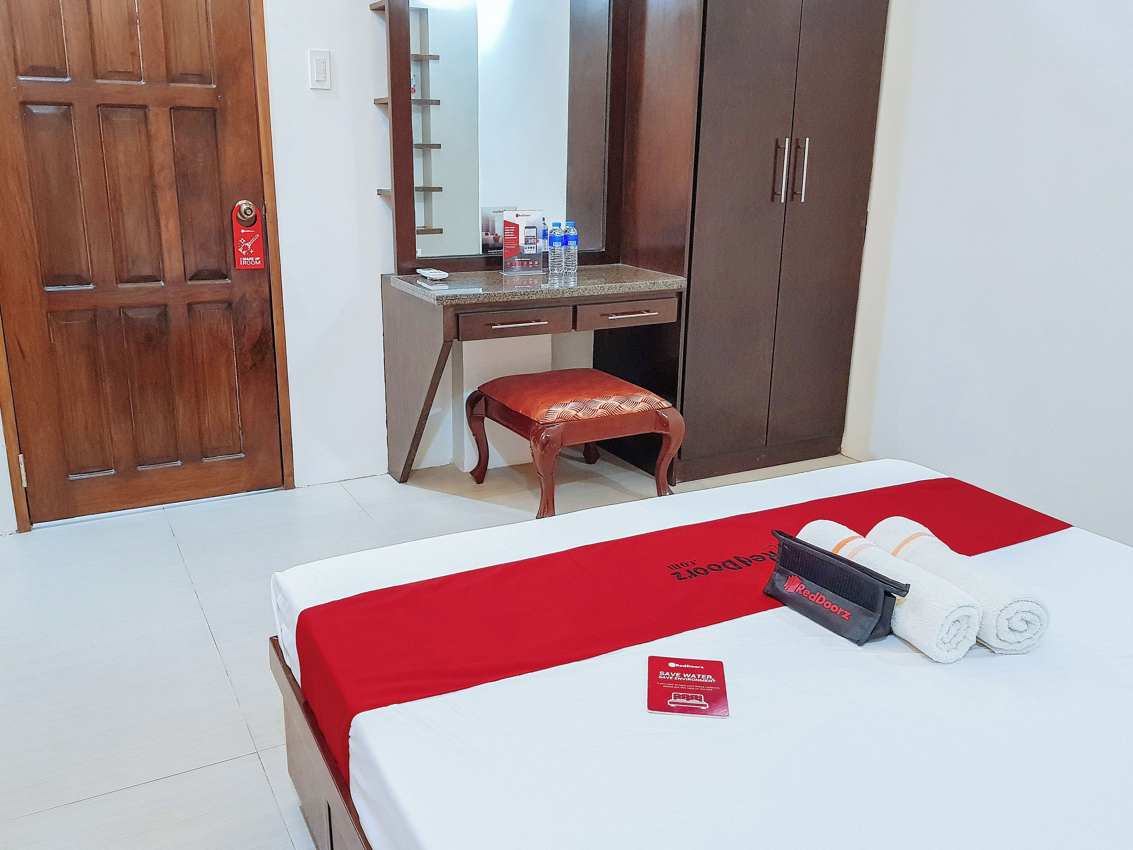 Habitació d'hotel amb llit, escriptori, cadira, armari i mirall.